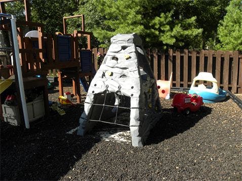 Playground with a climbing structure, playhouse, and toy vehicles