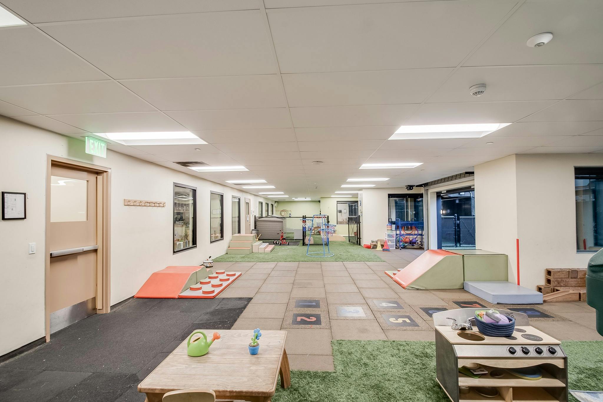 Indoor play area with soft mats, ramps, and small tables