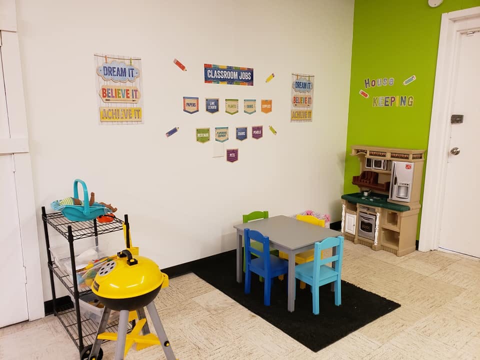 Playroom with small table and chairs, toy kitchen, and toy grill