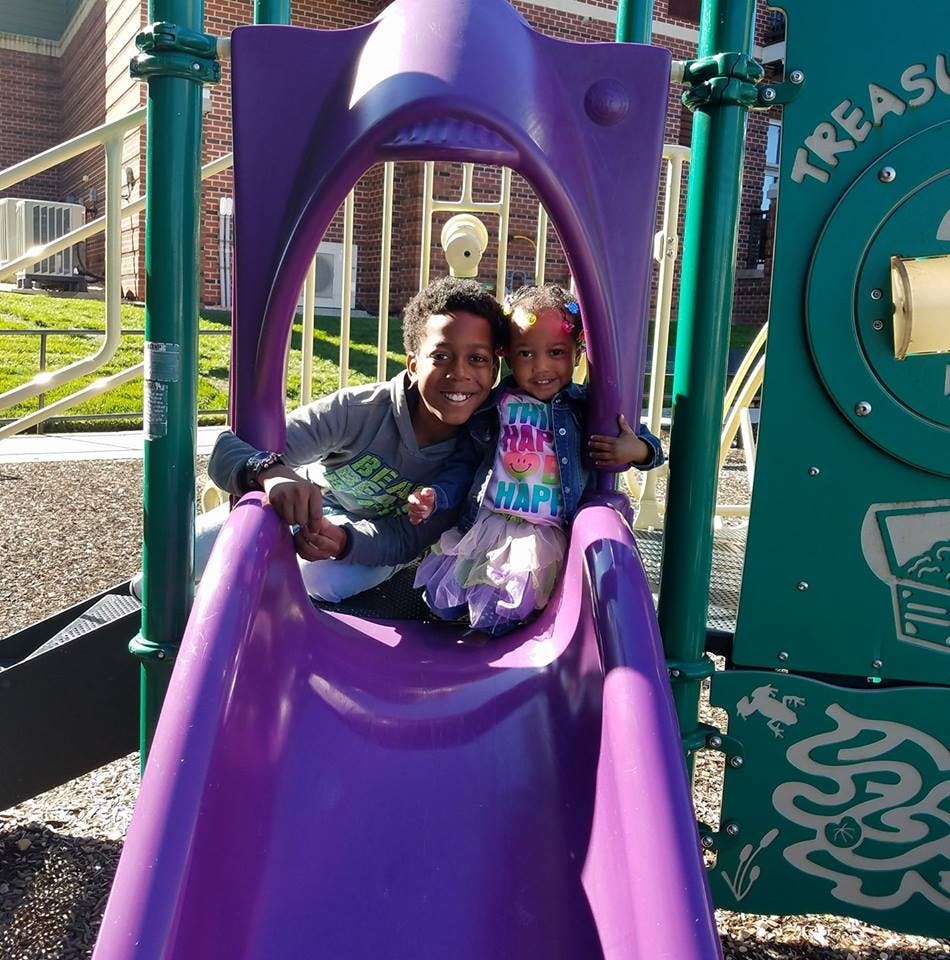 Two children on a purple playground slide