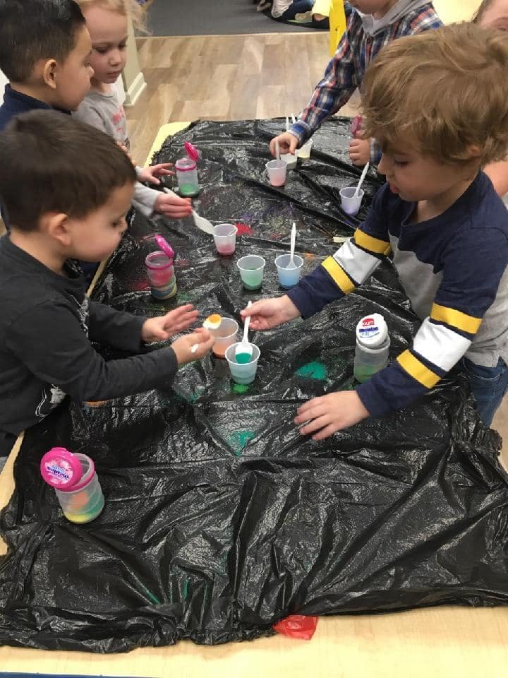 Children gathered around a table with cups and spoons, engaged in an activity