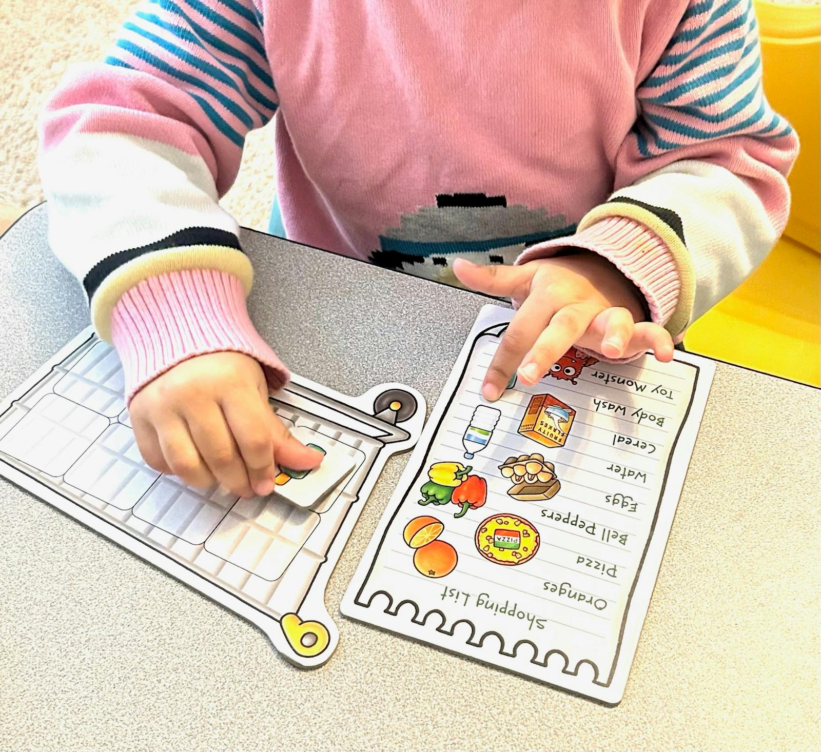 Child playing with a shopping list and grocery cart toy