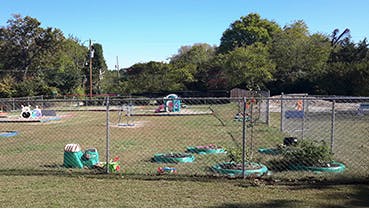 Playground with swings and play structures behind a chain link fence