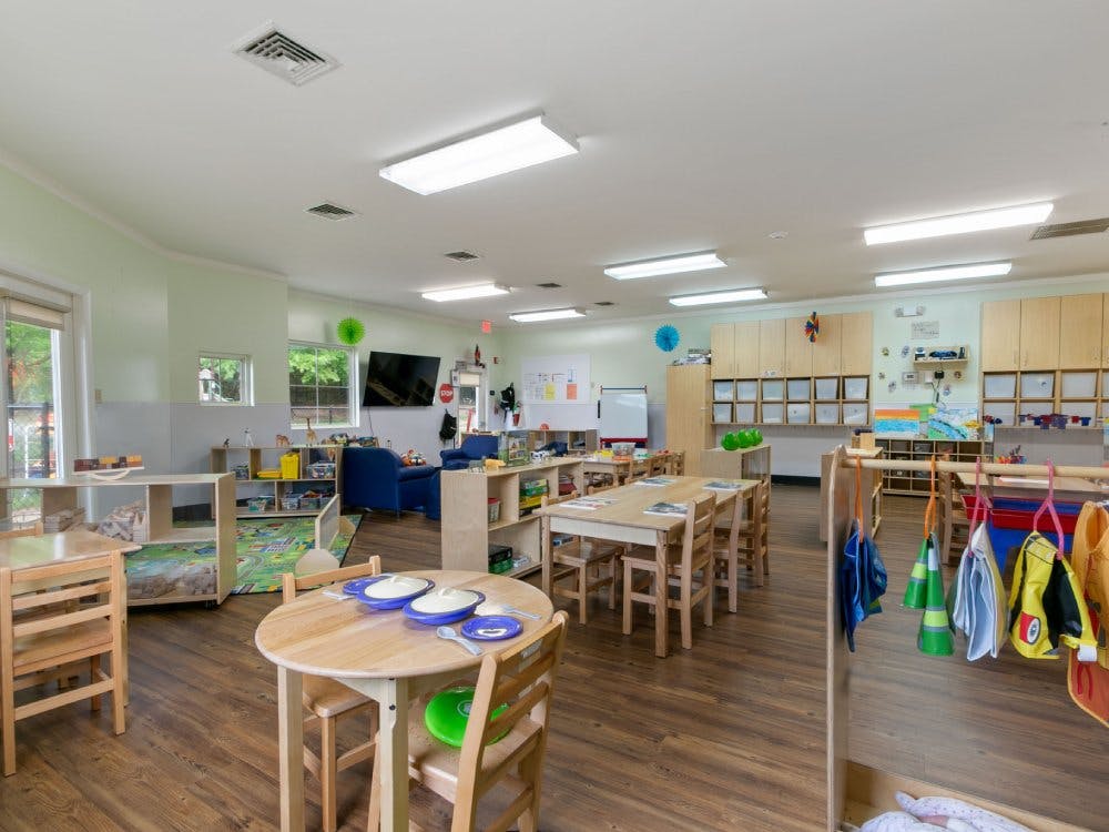 Classroom with small tables and chairs, shelves with toys, and cubbies