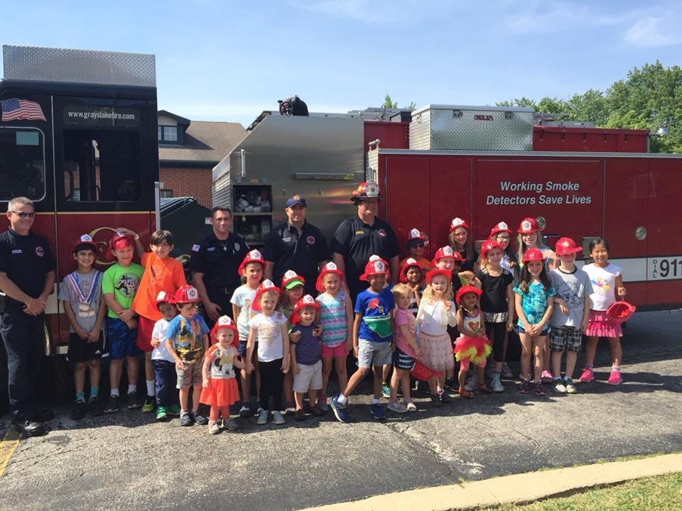 Firefighters and children in front of a fire truck
