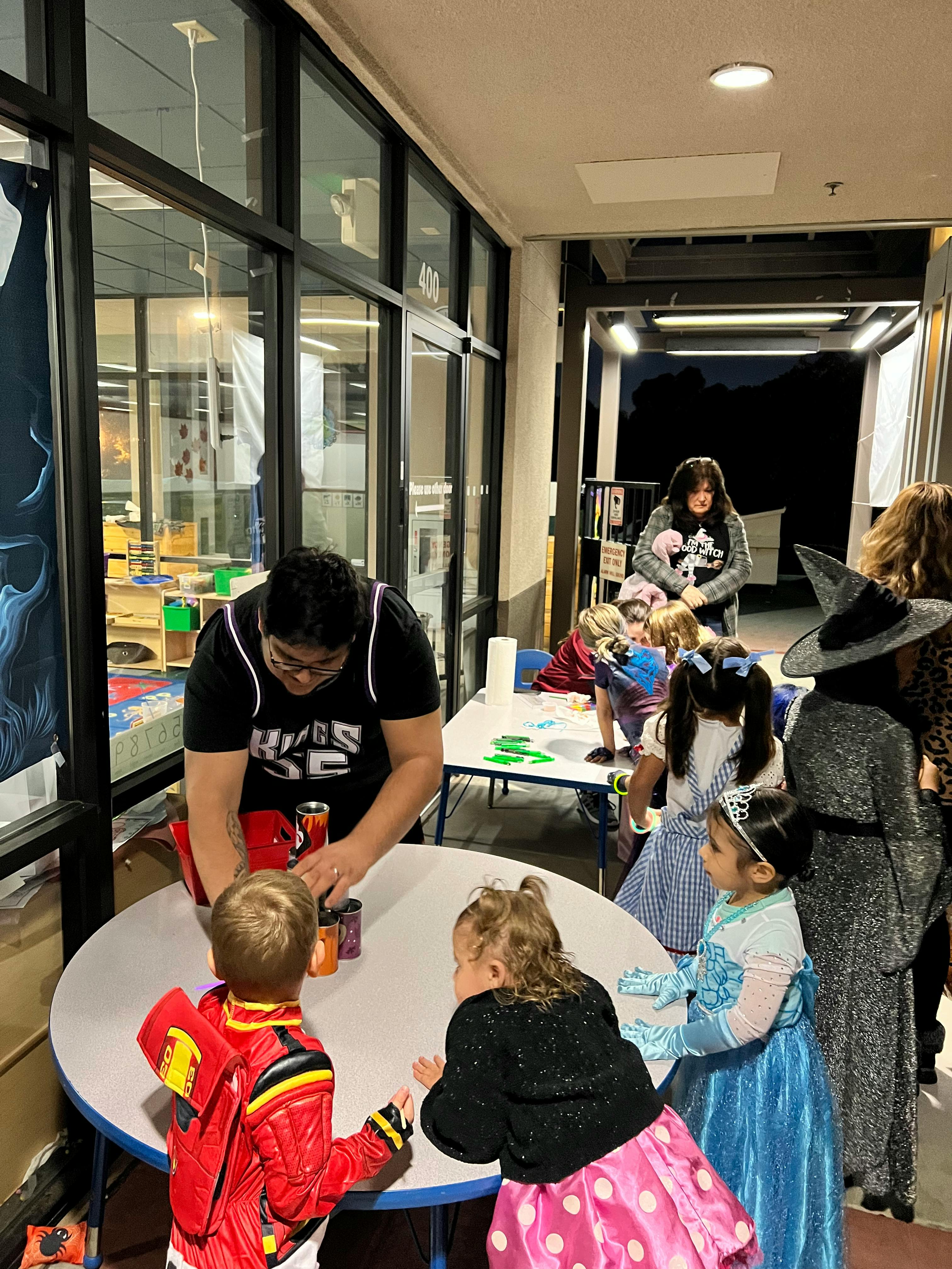 Person helping children with cans at a table
