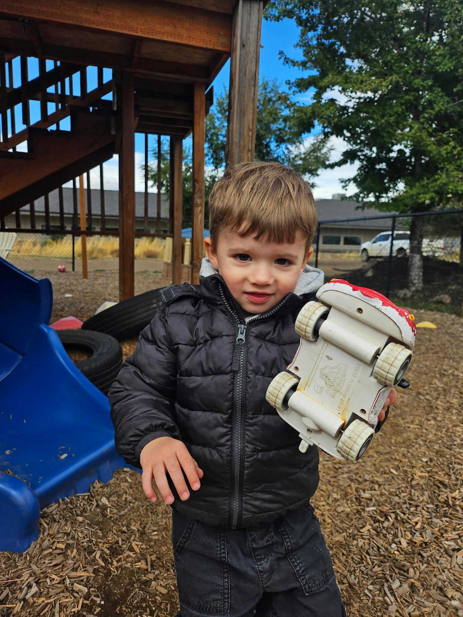 Child holding a toy car on a playground