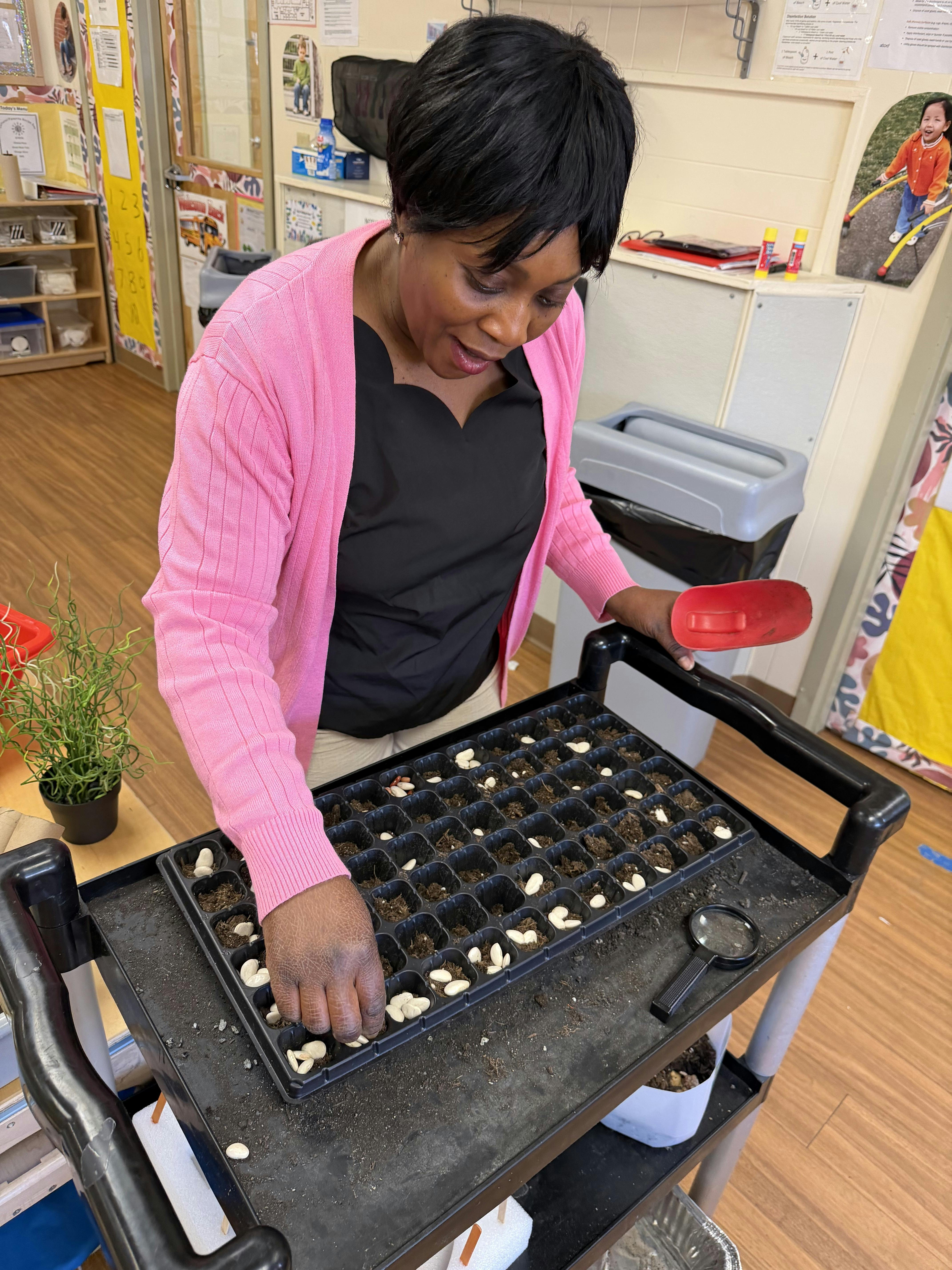 Person in a classroom planting seeds in a tray