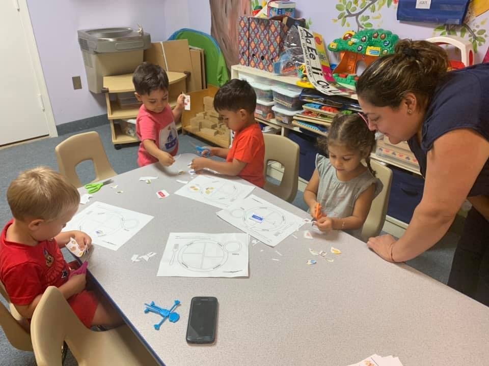 Adult supervising children at a table with papers and crafts