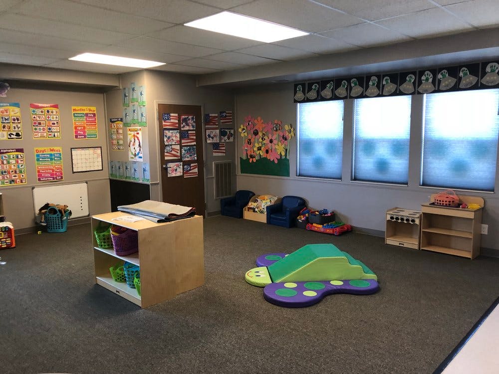 Playroom with colorful posters, small chairs, and a caterpillar-shaped play mat