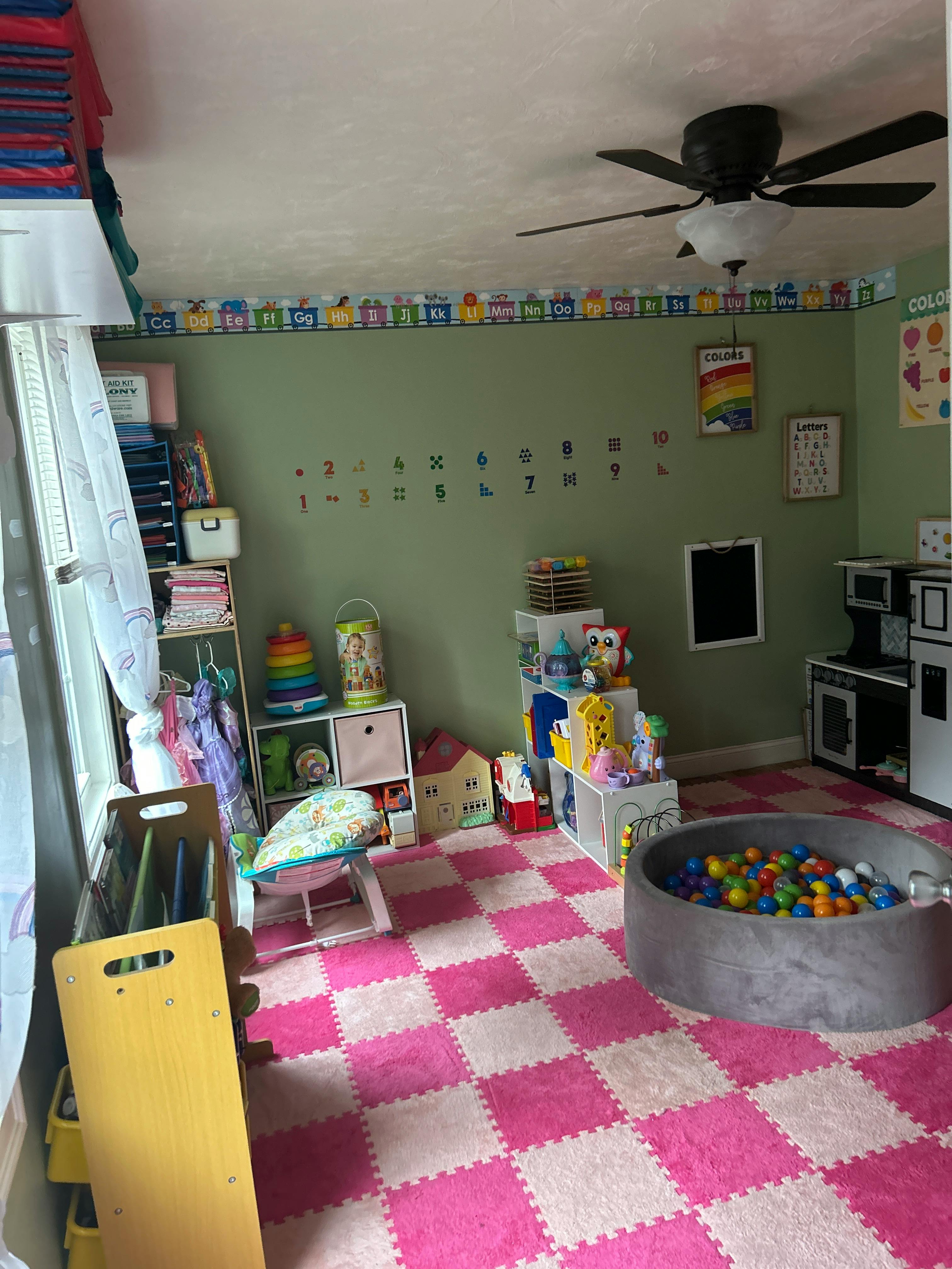 Playroom with pink and white checkered floor, toys, and a ball pit