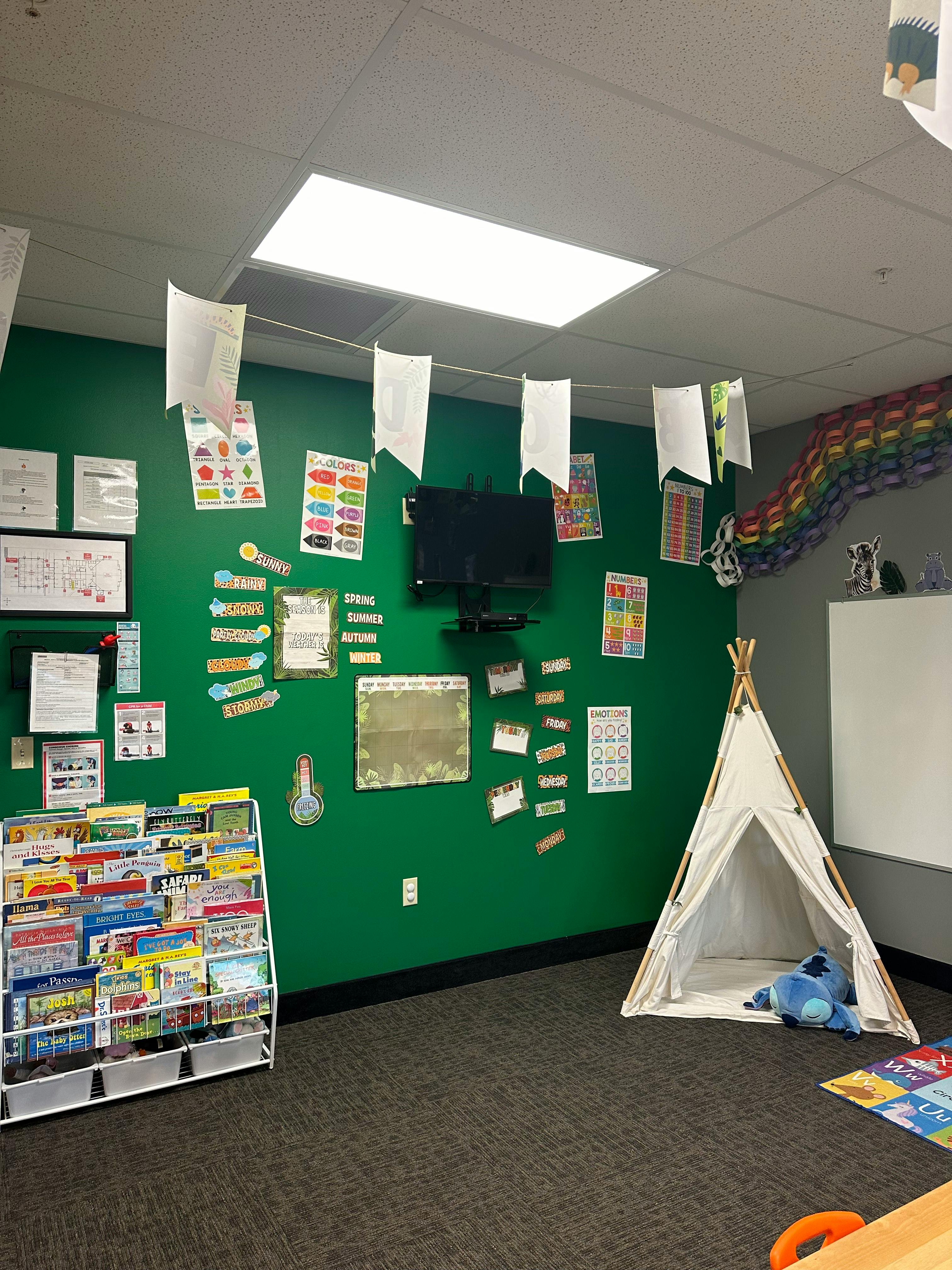 Classroom with green wall, book display, and small teepee