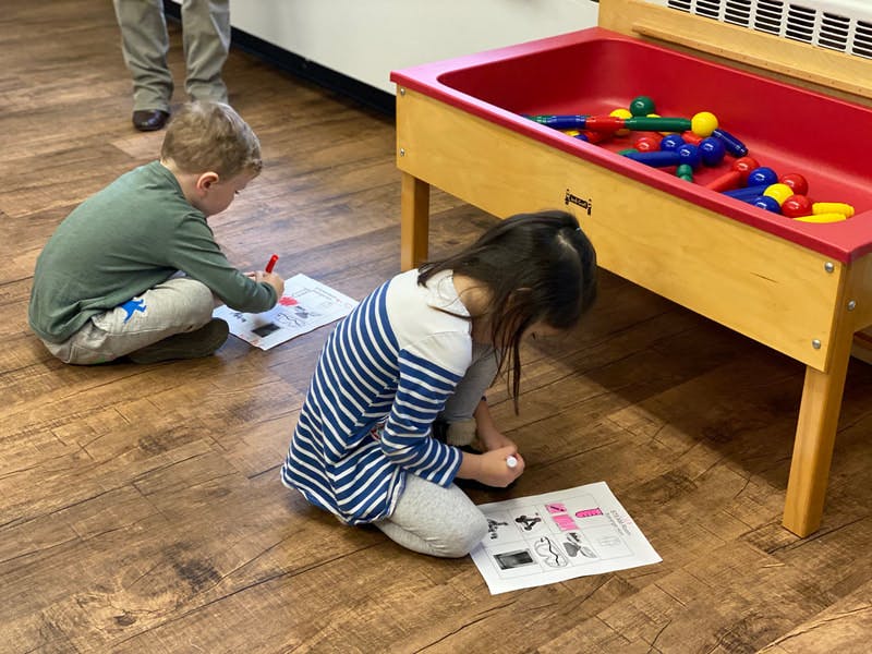 Two children drawing on paper on the floor