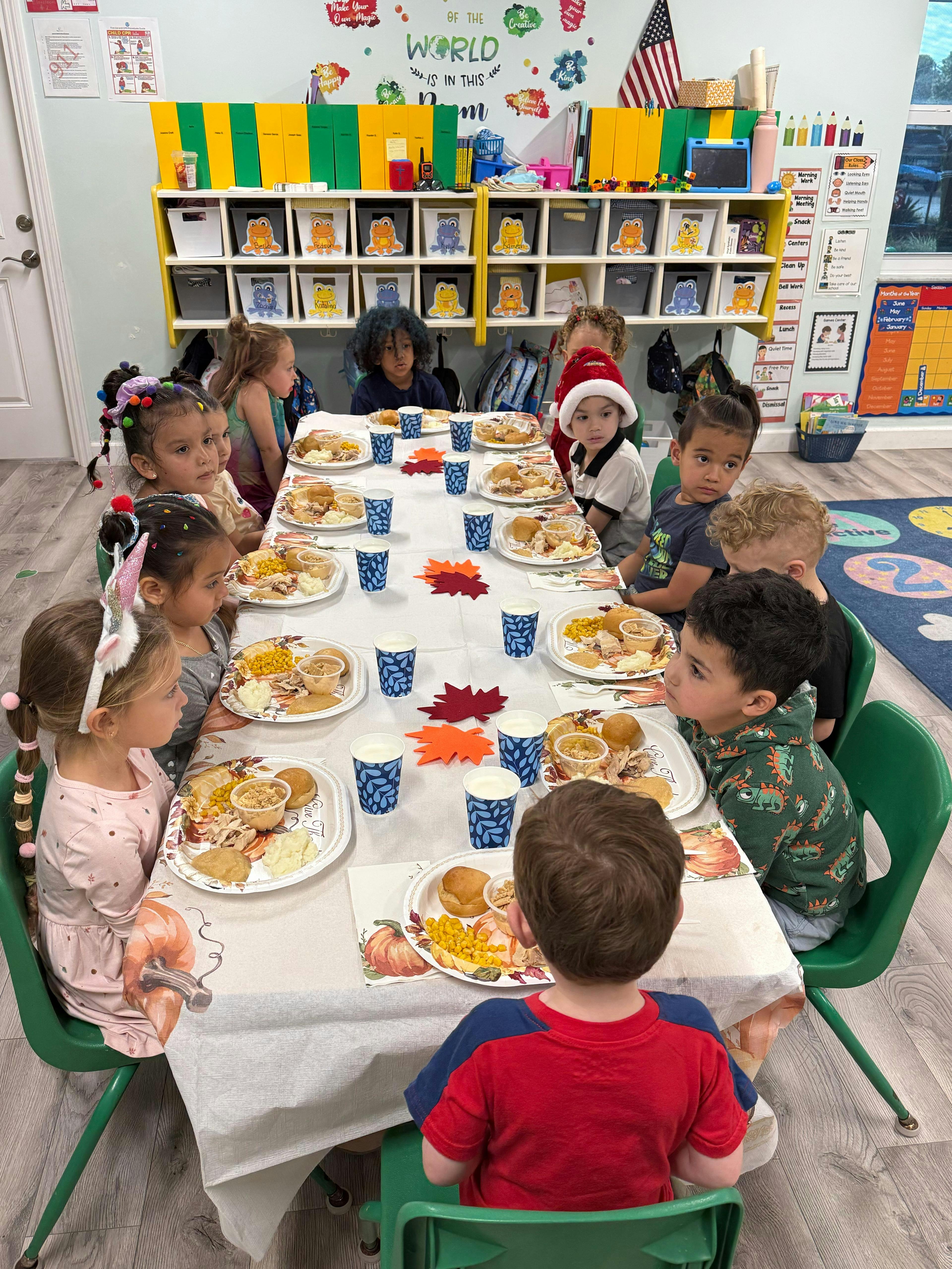 Children sitting at a table with plates of food in a classroom