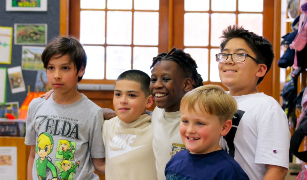 Five children standing together in a classroom