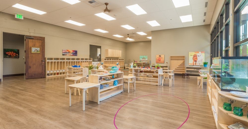 Empty classroom with small tables, chairs, and shelves