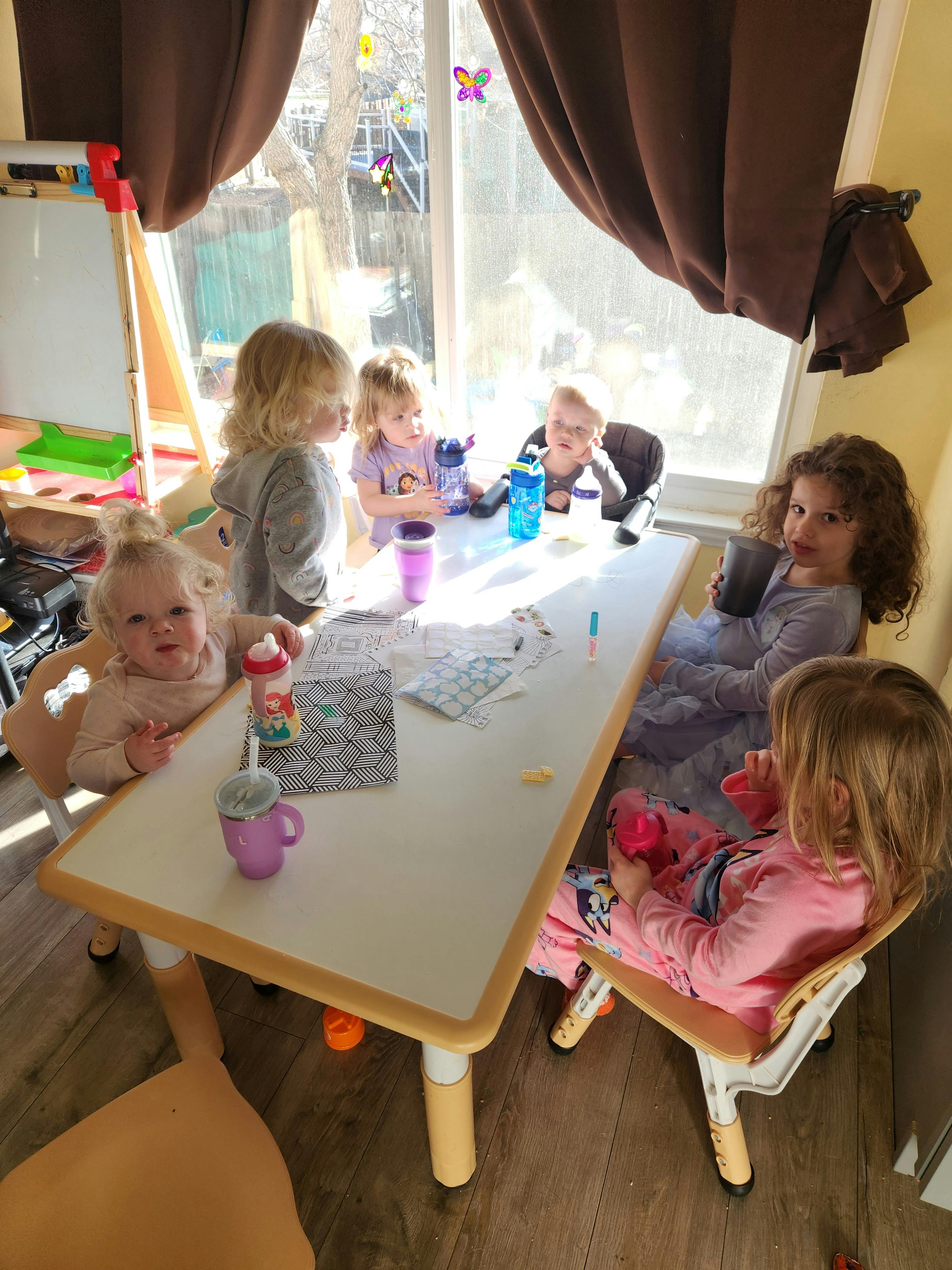 Multiple children seated around a light-colored table