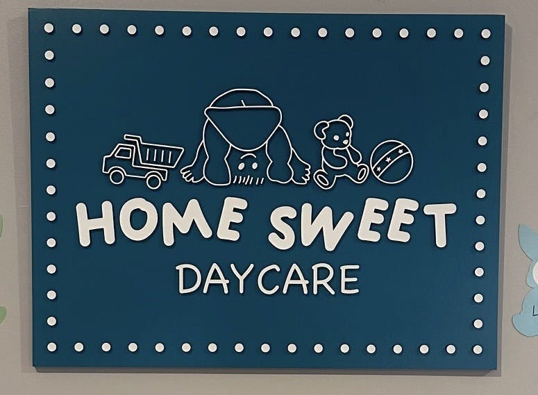 Sign reading Home Sweet Daycare with illustrations of a child and toys