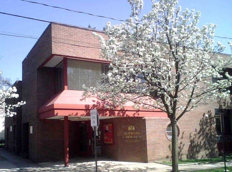 Brick building with red awning and a tree with white blossoms