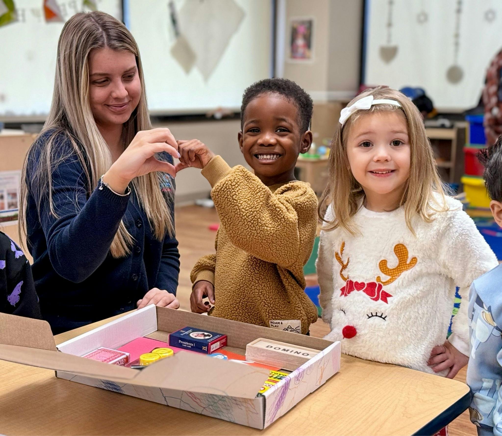 Adult and two children interacting with items in a box