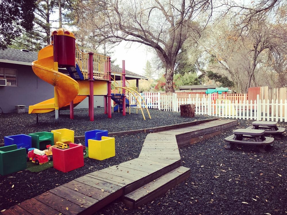 Playground with a yellow slide, colorful blocks, and picnic tables