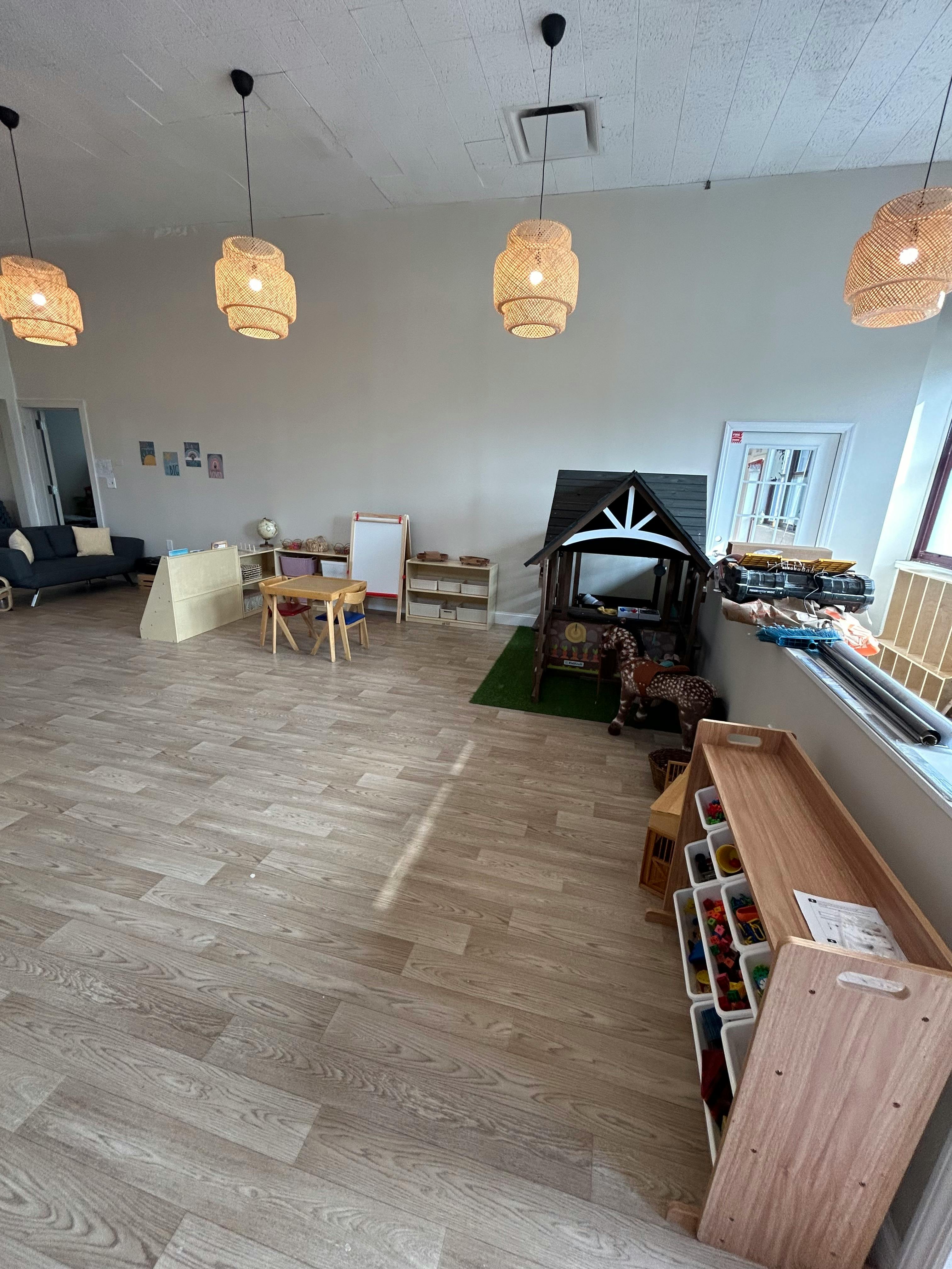 Playroom with small table and chairs, toy house, and storage shelves