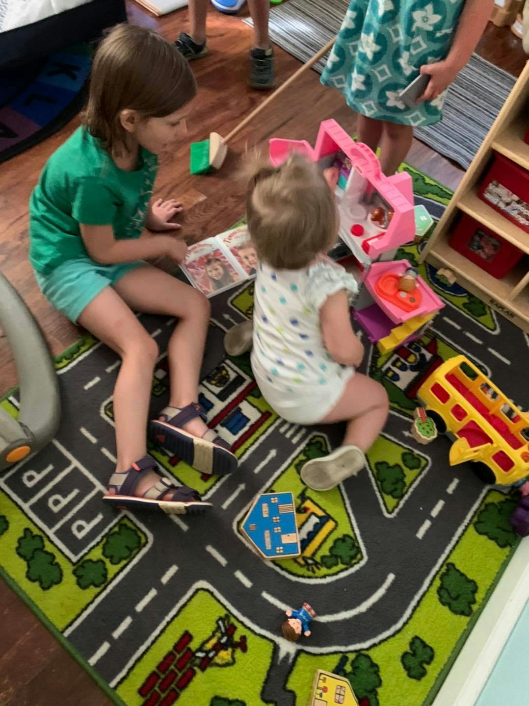 Two children playing on a road map rug with toys