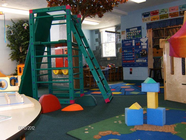 Indoor playground with a green climbing structure and colorful blocks