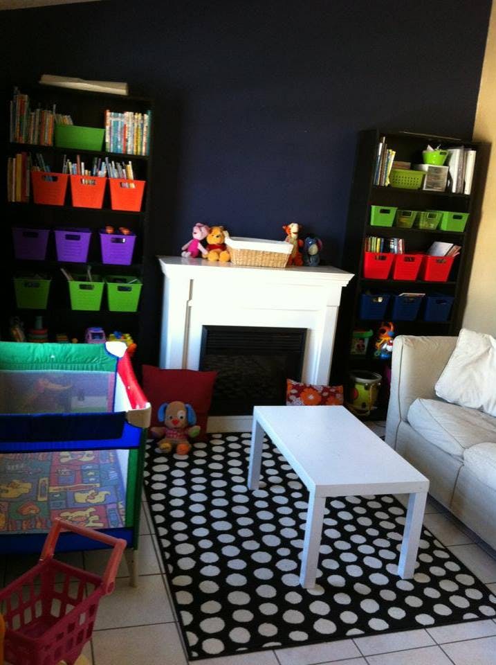 Playroom with bookshelves, fireplace, crib, and polka dot rug