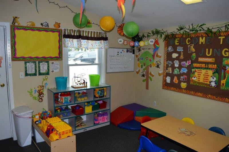 A colorful classroom with toys, a bulletin board, and a small table