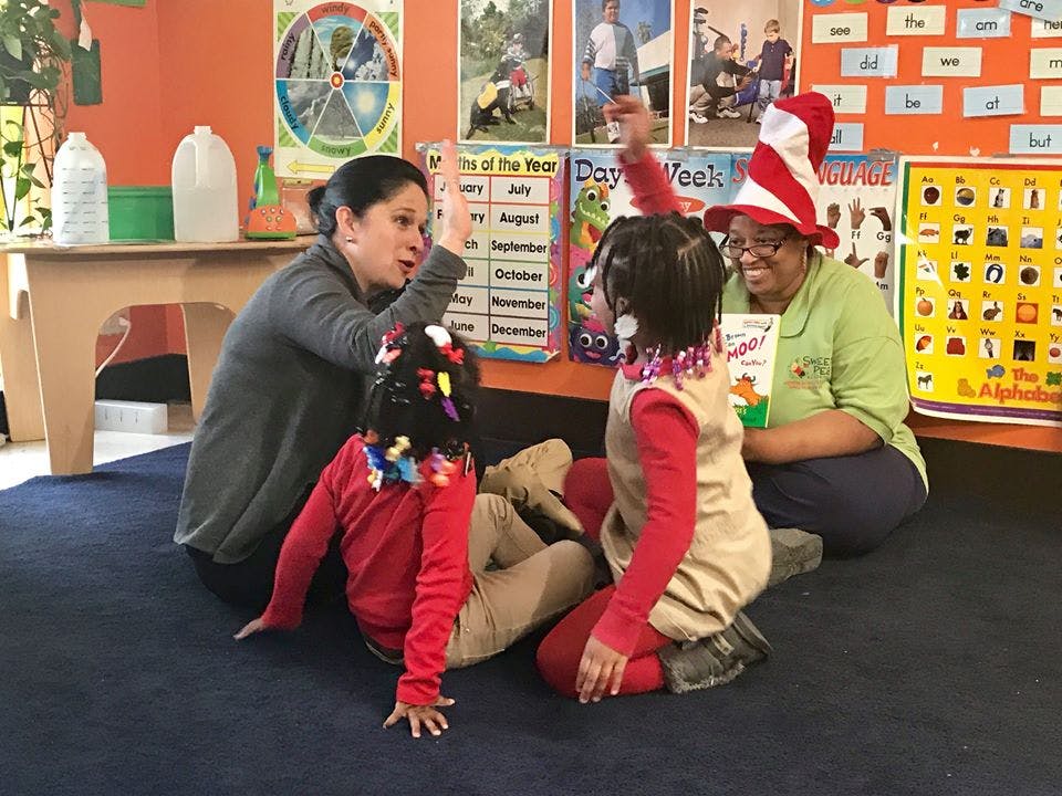Two adults and two children sitting on the floor in a classroom