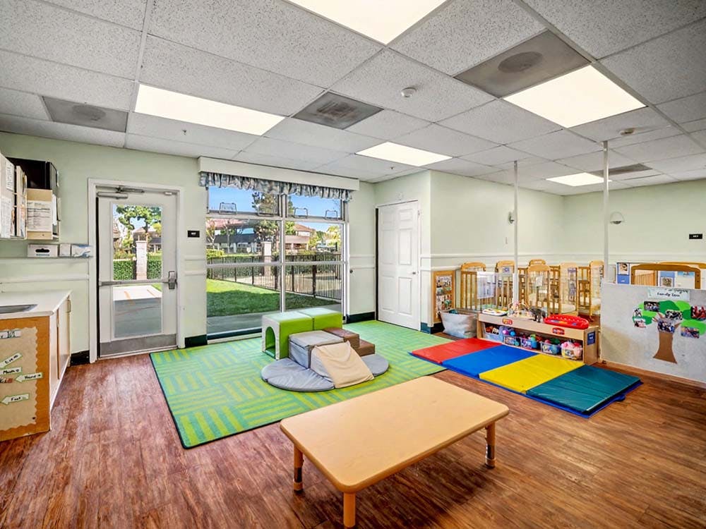 A playroom with cribs, play mats, and a small table