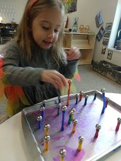 Child playing with magnetic sticks and balls on a tray