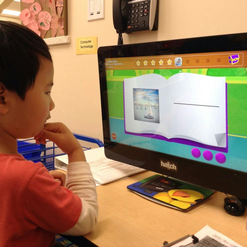 Child looking at a computer screen displaying an open book graphic