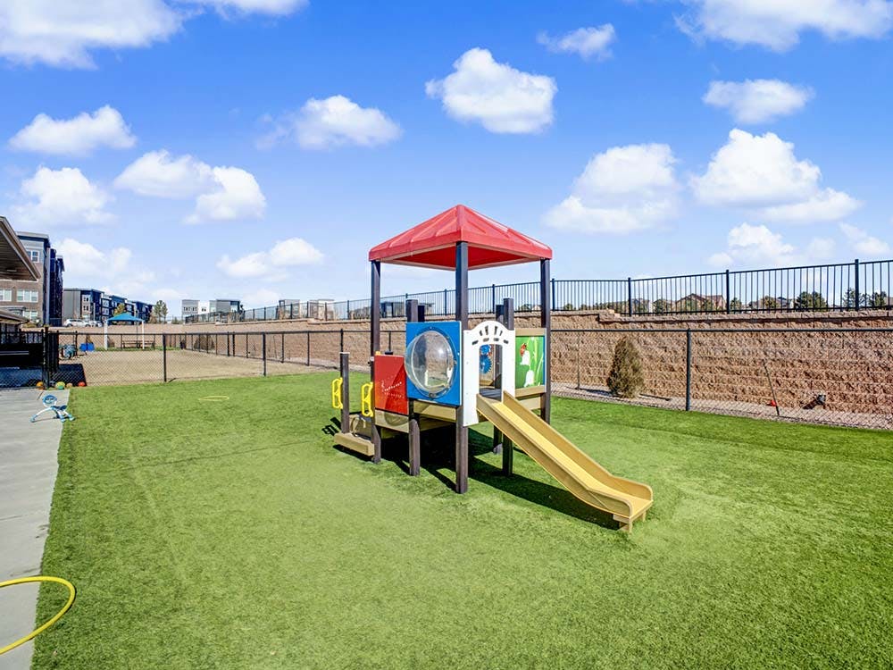 Colorful playground structure with a yellow slide on artificial turf