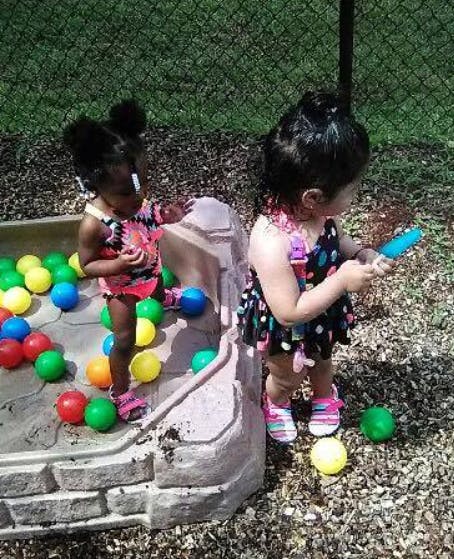 Two children playing with colorful balls in a ball pit