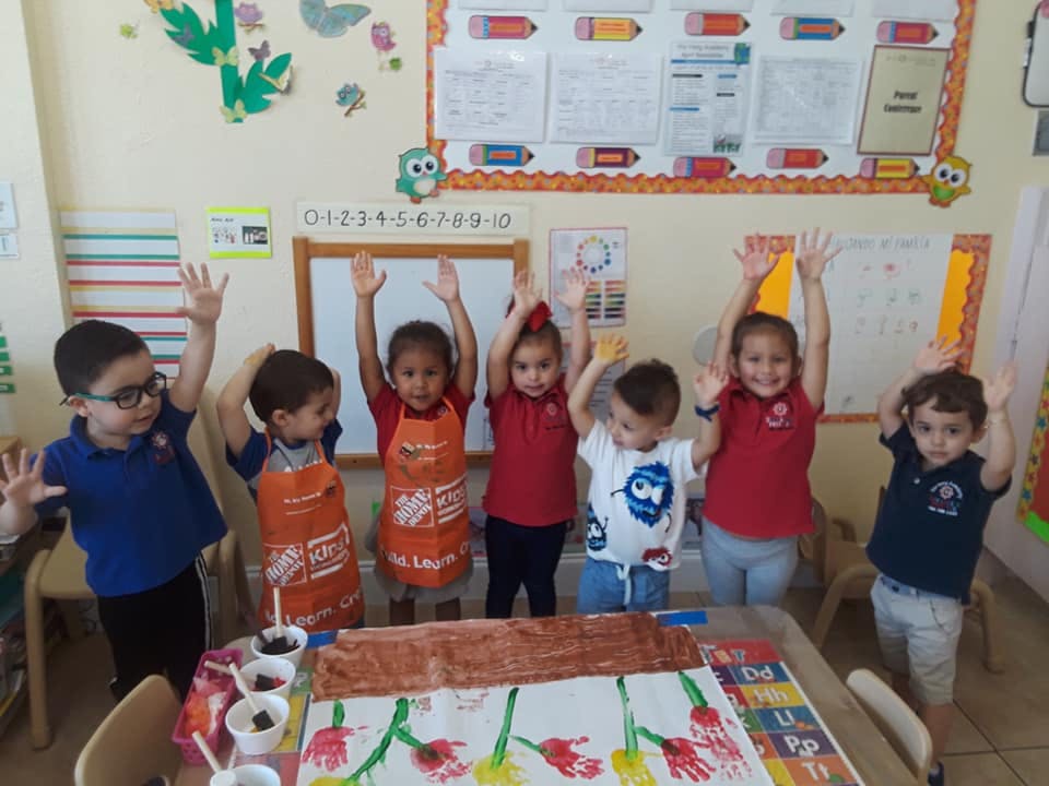 Group of children with hands raised in a classroom