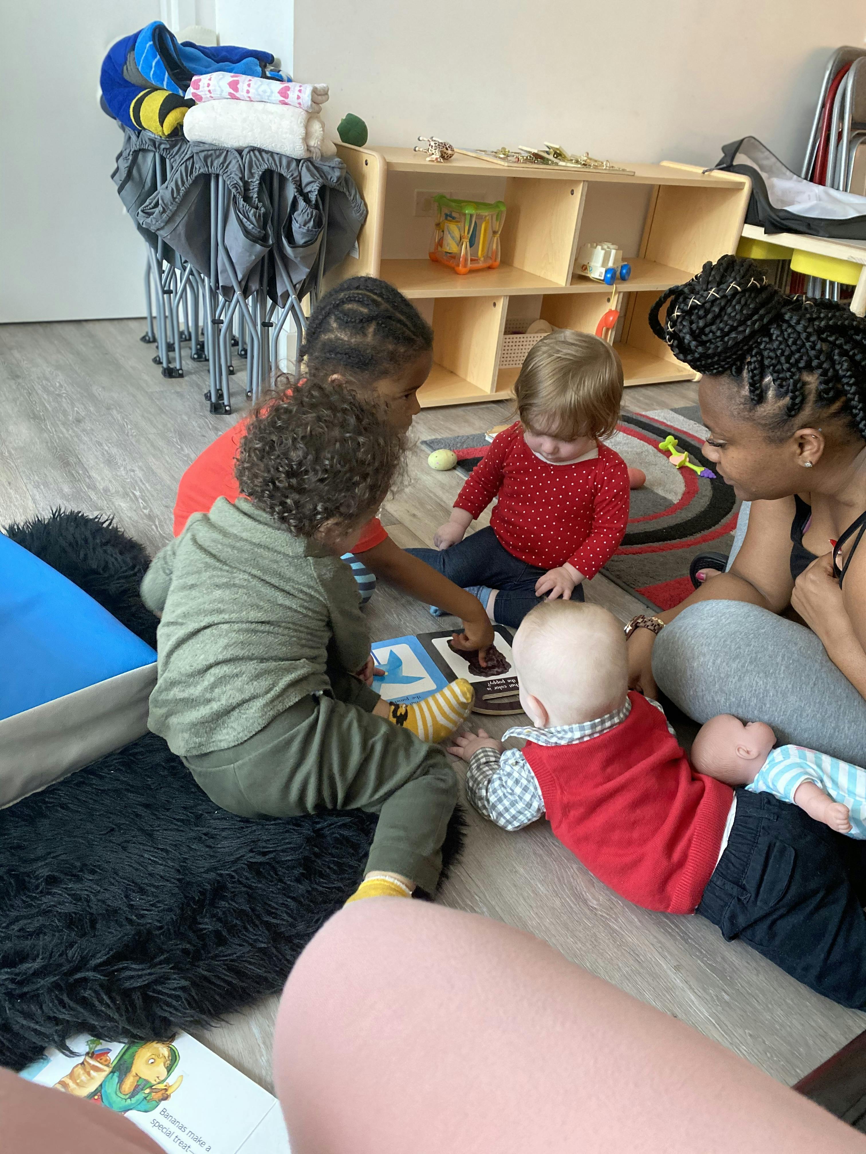 Adult and three children sitting on floor playing with toys