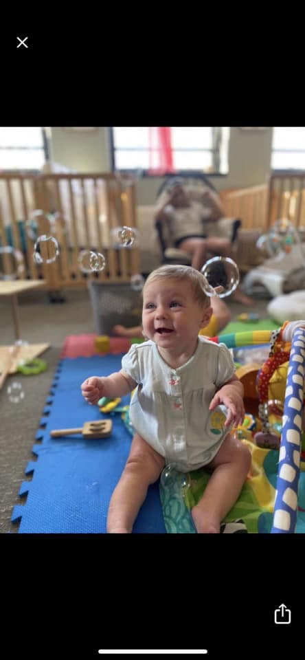 Child sitting on a playmat with bubbles floating around
