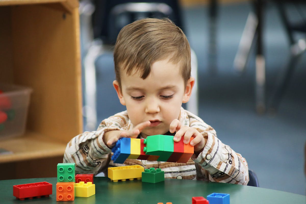 Child playing with colorful building blocks at a table