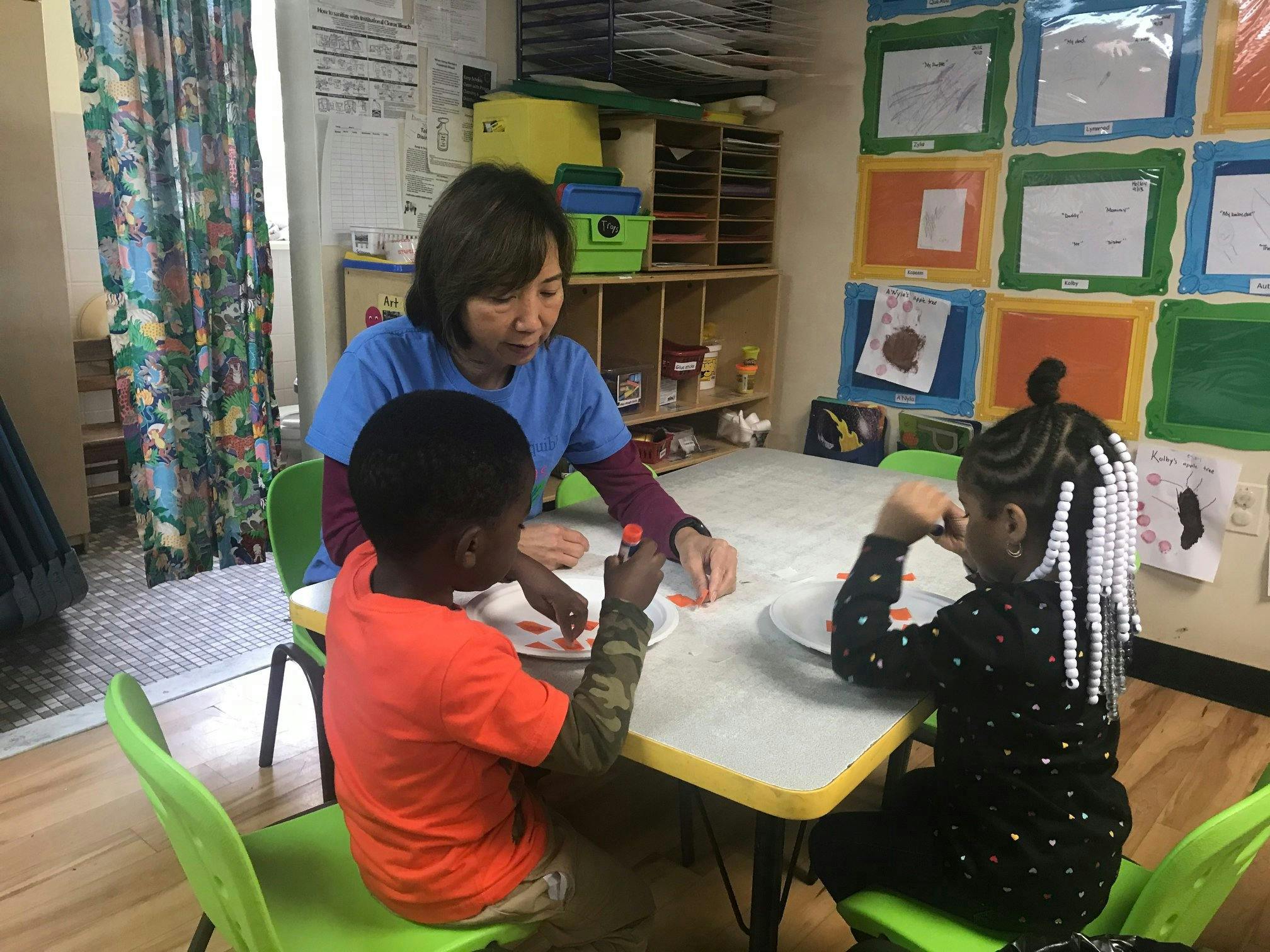Person and two children at a table in a classroom