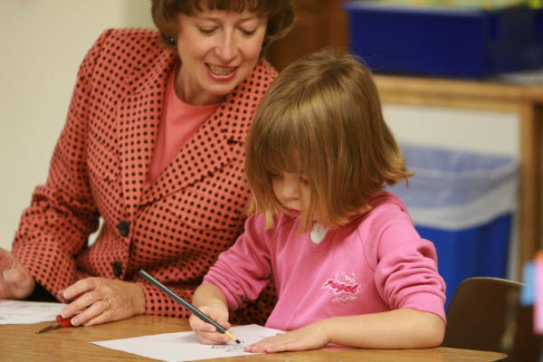 Adult and child writing on paper at a table