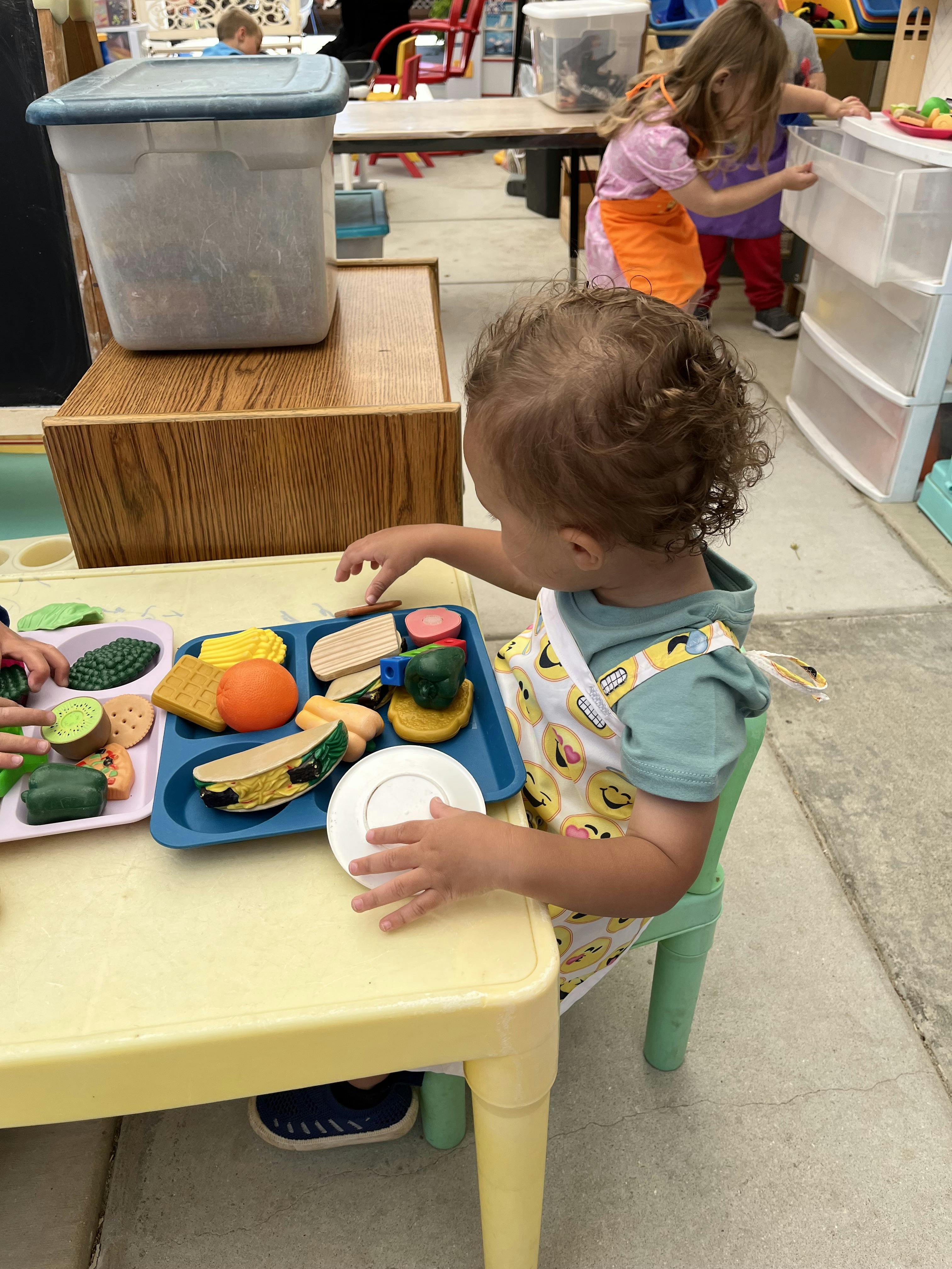 Child playing with toy food at a small table
