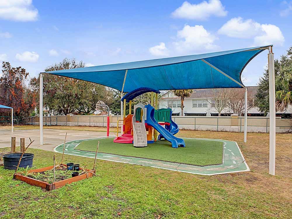 A blue shade cover over a playground with a colorful slide structure