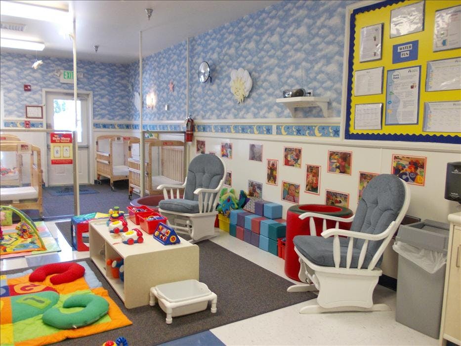 daycare classroom with multiple cribs, rockers, and play mats
