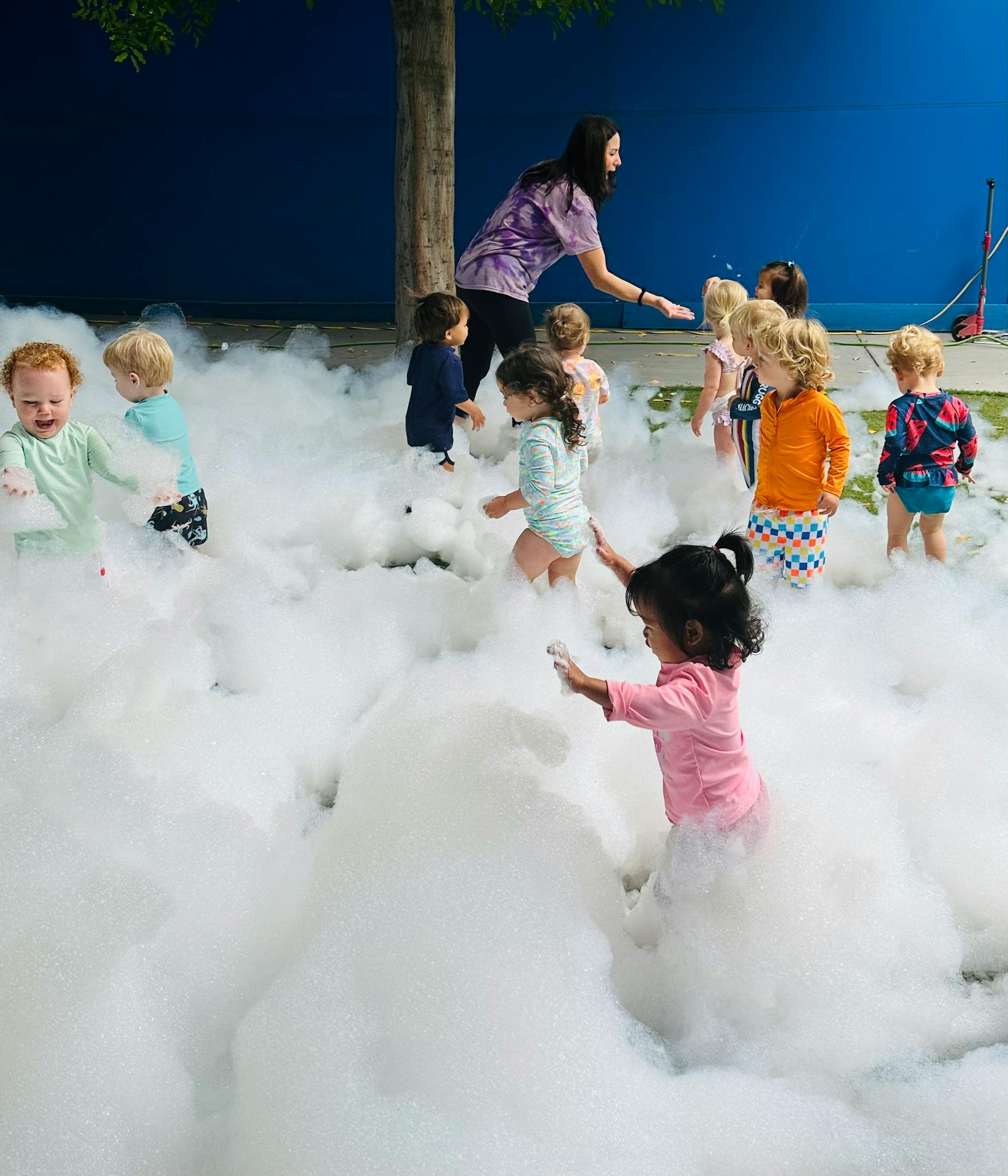 Adult and children playing in a large pile of foam