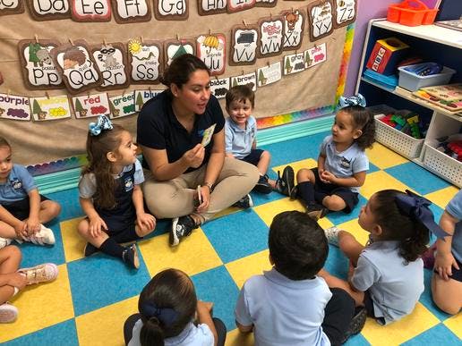 Person sitting on floor with children in a classroom