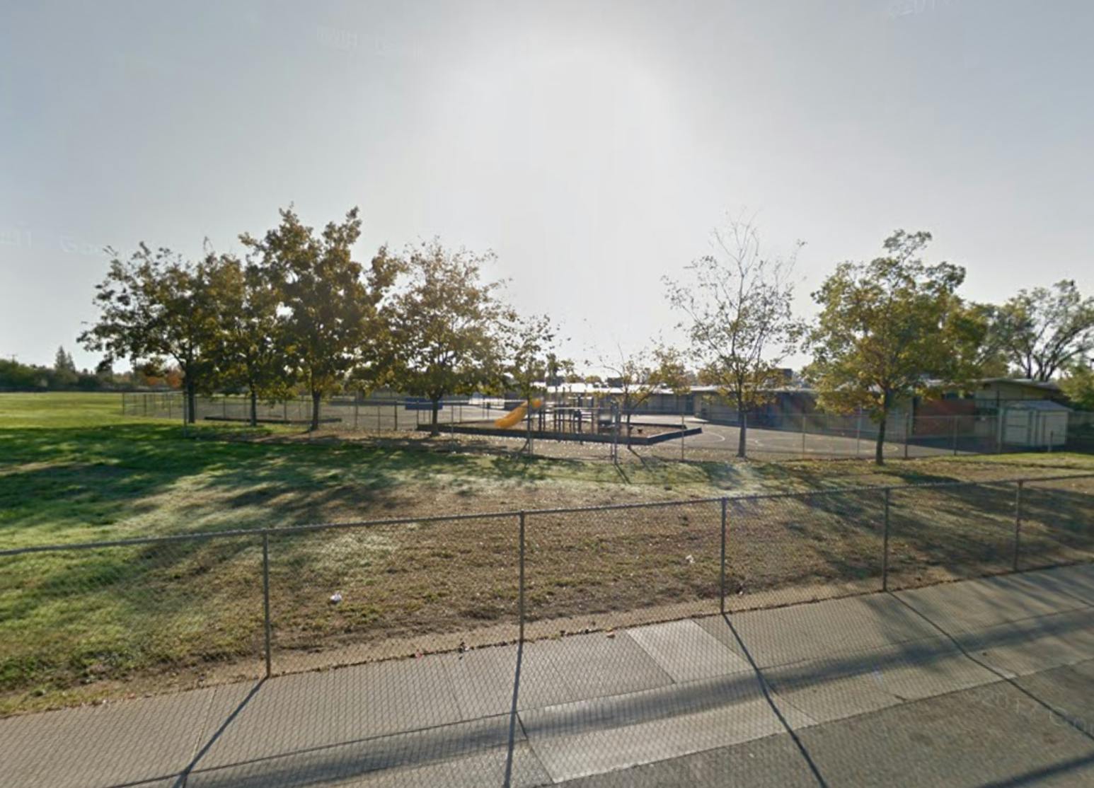 Playground with swings and slides behind a fence