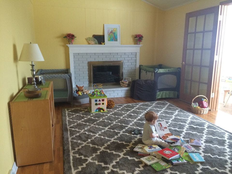 Child sitting on a rug surrounded by books