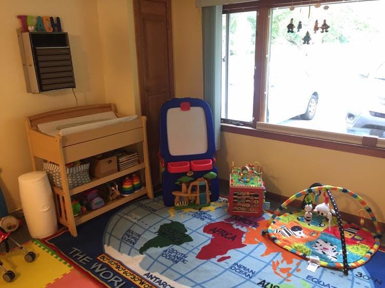 Nursery room with changing table, easel, and playmat on a world map rug